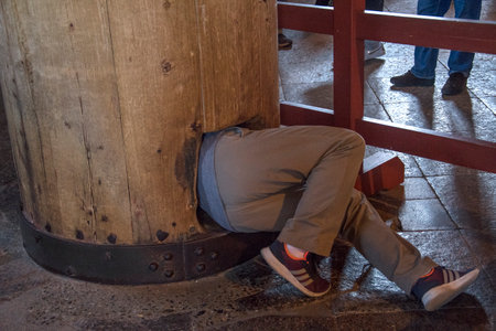 Nara, Japan- 27 Nov, 2019: An adult try to crawl through hole of a big wooden pillar for blessing inside the Todaiji, Nara.のeditorial素材