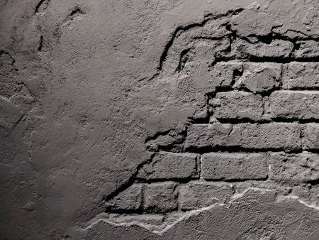 Damaged vintage black wall with cracked bricks