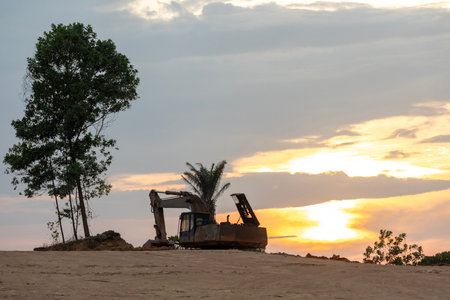Excavating machinery at the construction site, sunset in background.