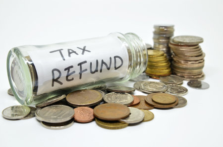 Tax refund lable in a glass jar with coins spilling out isolated on white background