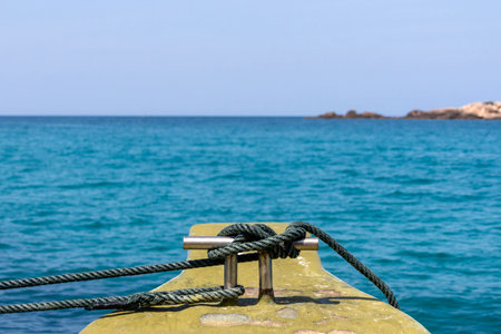 Rope tied on boat cleat with crystal blue sea water.の写真素材