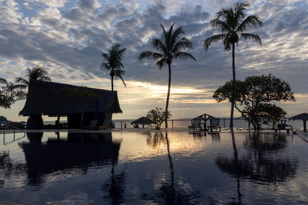 Sunrise over the swimming pool in a hotel with the reflection of the sky on the pool.の写真素材