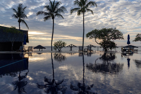 Sunrise over the swimming pool in a hotel with the reflection of the sky on the pool.の写真素材
