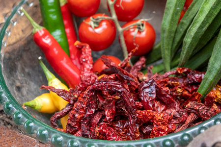Dried and fresh chili, red tomato and okra in a glass bowl