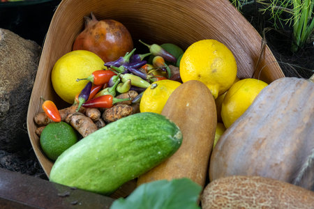 Assorted organic vegetables and fruits in a basket, including lemon, lime, turmeric, squash, and...