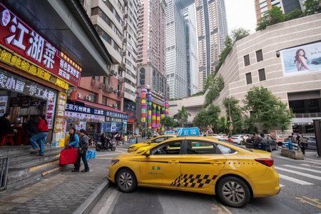 Chongqing, China- 2 Nov 2025: Iconic yellow taxi travels on the street in Chongqing with the Raffles City skyline in background.のeditorial素材