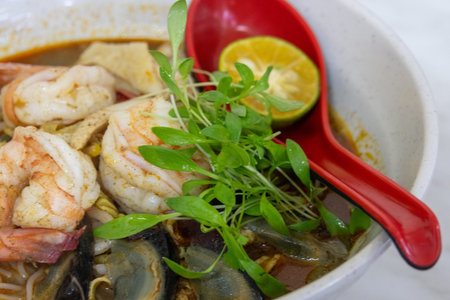 Sarawak Laksa, a renowned Malaysian noodle soup, featuring a distinctive, savory, and aromatic...