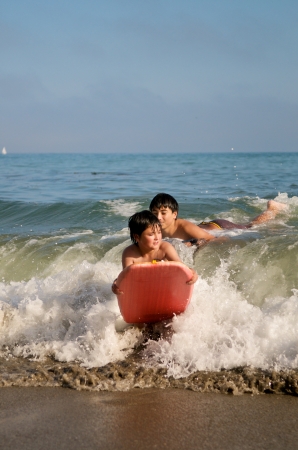 Boys surfing on the beach with boogie boardsの写真素材