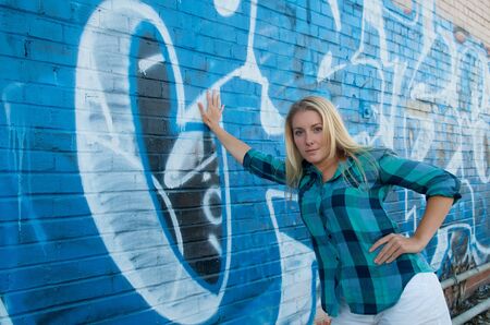 Blond girl in front of a graffiti wallの写真素材