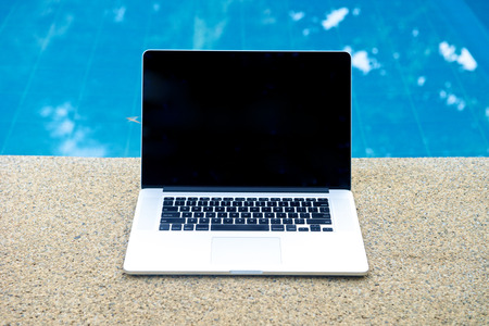 Laptop by the pool, working on vacation with mobility conceptの写真素材