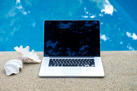 Laptop by the pool, working on vacation with mobility conceptの写真素材