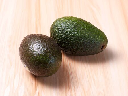 Green Avocados on wooden board