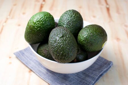 Avocados in a bowl on wood board