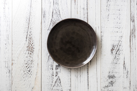 Black Round Plate on white wooden table backgroundの写真素材