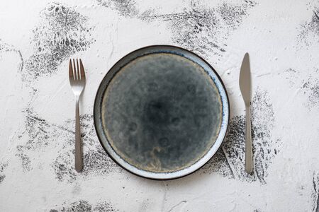 Round Plate with utensils on white scraped wooden table backgroundの写真素材