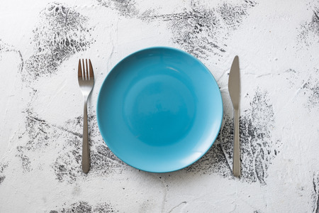 Blue Round Plate with utensils on white scraped wooden table backgroundの写真素材