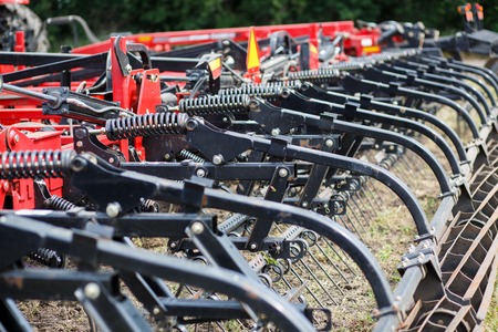 Modern tech red tractor plowing a green agricultural field in spring on the farm. Harvester sowing wheat. Mechanismの写真素材