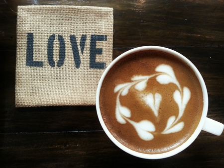 Coffee Latte on dark wood table with the word "LOVE" saucerの写真素材