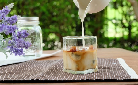 Relax with Ice Caffe Latte in the garden Milk pouring into a glass filled with espresso ice cubeの写真素材