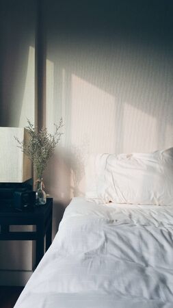 Warm morning light and shadow over a fluffy relax white bedの写真素材