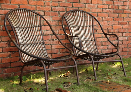 old wicker chairs in front of an old brick wallの写真素材