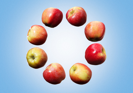 Circle of falling red and yellow apples in the air on the blue backgroundの写真素材