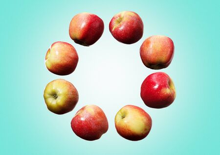 Circle of falling red and yellow apples on green backgroundの写真素材