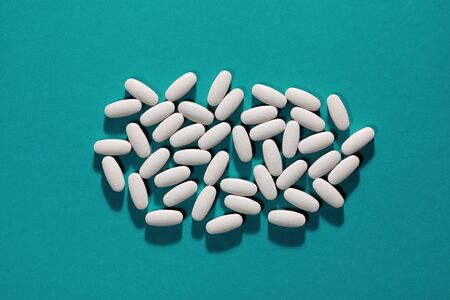 A bunch of white pills on the cyan backgroundの写真素材
