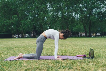 Young woman practicing yoga outdoors. Morning exercises.の写真素材