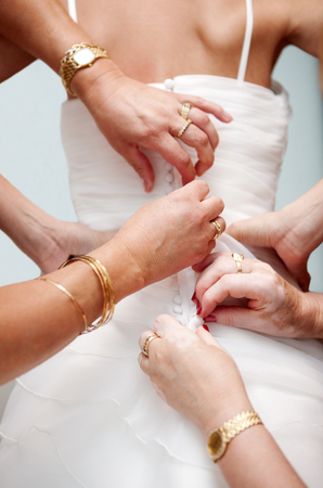 Woman helping hands to place the bride dress. Button from behind.の写真素材