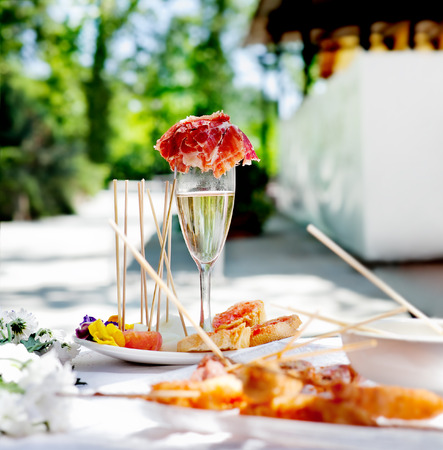 Outdoor catering. Food events and celebrations. Sliced ham and toast with champagneの写真素材