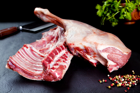 Fresh and raw meat. Ribs and pork chops uncooked, ready to grill and barbecue on black slate backgroundの写真素材
