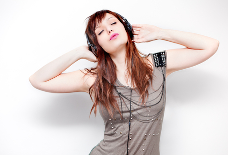 Beautiful young woman listening to music with headphones and singing on neutral background. Lifestyleの写真素材
