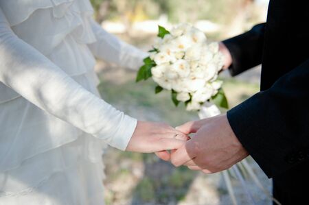 Closeup of a wedding couple holding hands, wearing a wedding ring の写真素材