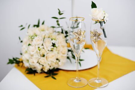 two decorated wedding glasses with a groom boutonniere and the brideの写真素材