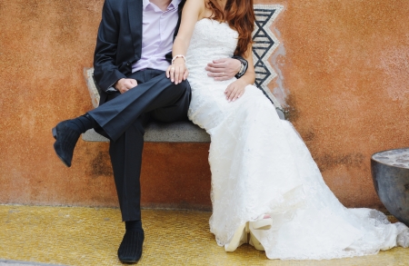 groom and bride sitting on a stone benchの写真素材