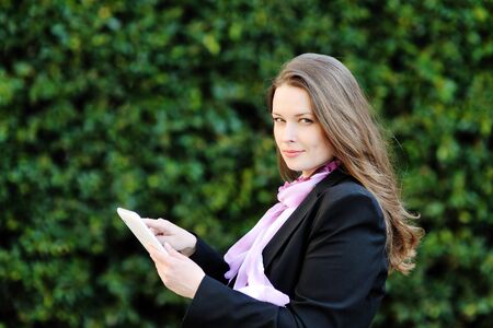 beautiful smiling woman with long hair using tablet computerの写真素材