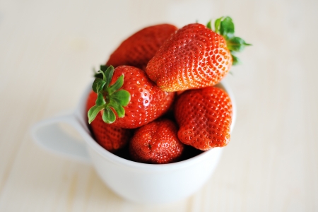 juicy delicious fresh red strawberries in a white cupの写真素材