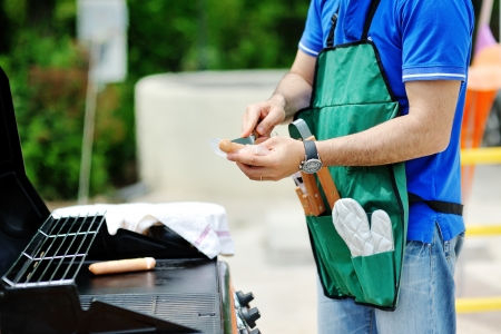 Man at the barbecue grill preparing sausages for a garden partyの写真素材