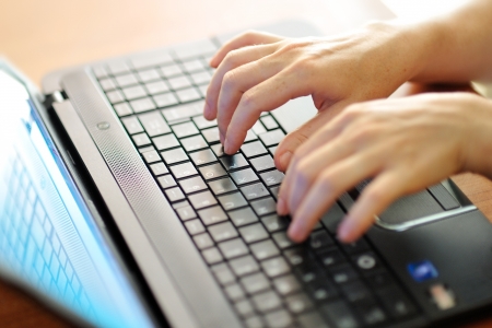 woman hands typing on a black laptop computer keyboardの写真素材