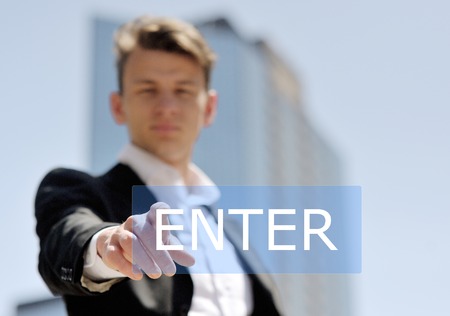 man pushing virtual enter button on business building background - technology, internet and networking conceptの写真素材