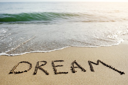 dream word written on the sand of the beach - positive thinking conceptの写真素材