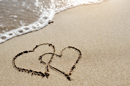 love concept - two hearts drawn on the sand of the beachの写真素材