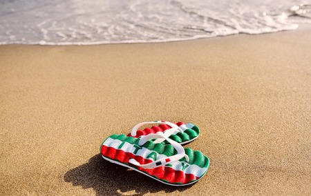 flip flops with the word Italy on the sand of beach - holidays and relaxation concept