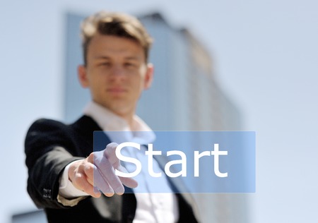 man pushing virtual start button on business building background - technology, internet and networking conceptの写真素材