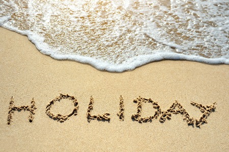 holiday written on the sand beach near seaの写真素材