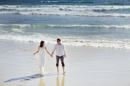bride and groom together holding hands near sea in wedding dayの写真素材
