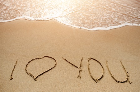 Love message written on the sand beach near seaの写真素材