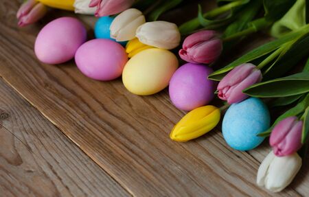 Easter eggs and colored tulips flowers on wooden backgroundの写真素材