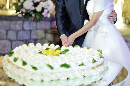 Bride and groom cutting heart shaped wedding cake at wedding receptionの写真素材